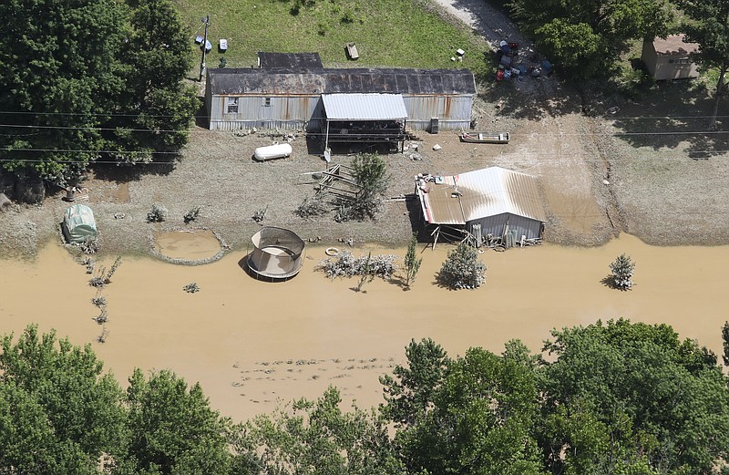 in this aerial photo, some homes in Breathitt County, Ky., are still surrounded by water on Saturday, July 30, 2022, after historic rains flooded many areas of Eastern Kentucky killing multiple people. A thin film of mud from the retreating waters covers many cars and homes. (Michael Clevenger/Courier Journal via AP)