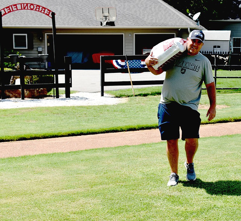 MARK HUMPHREY  ENTERPRISE-LEADER/Kurt Wing, a Bentonville P.E. teacher, carries maintenance material out onto Perronni Field, site of a little league baseball tournament hosting the Peronni Invitational Aug. 20-21 in the Weddington area. The tournament serves as a fundraiser to address Alzheimer’s disease. Volunteers are needed to help staff this year's tournament and may sign up by emailing Sam Perronni at sperronni1@hotmail.com.