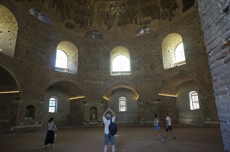 Visitors admire the Byzantine mosaics adorning the gigantic dome of the Rotunda on Saturday, June 25, 2022, in Thessaloniki, Greece. The circular building was built as a Roman temple or mausoleum in the 300s, shortly after became a Christian church, later on a mosque &#x2013; and is now a museum, though liturgy is still celebrated a few times a year. (AP Photo/Giovanna Dell'Orto)