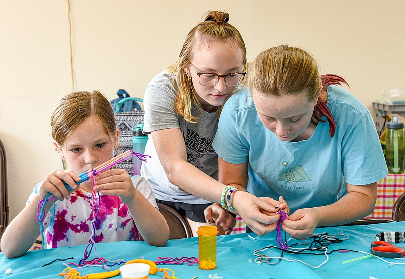 News Tribune file photo: Haley Ganey, 13, right, shows her sister Addison, 17, how to add beads to a yarn bracelet to finish it. Seated at left is Phoebe Cain, 7, who is working on a yarn bracelet. They were at Capital Arts for an art camp.