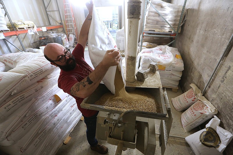 Eric Morris pours malt into a hopper while making beer on Wednesday, Aug. 3, 2022, at Lost Forty Brewing in Little Rock. 
(Arkansas Democrat-Gazette/Thomas Metthe)