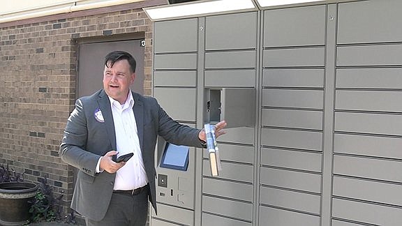 Adam Webb demonstrates the remote locker at National Park College, from which library card holders can pick up materials they've checked out. – Photo by Courtney Edwards of The Sentinel-Record