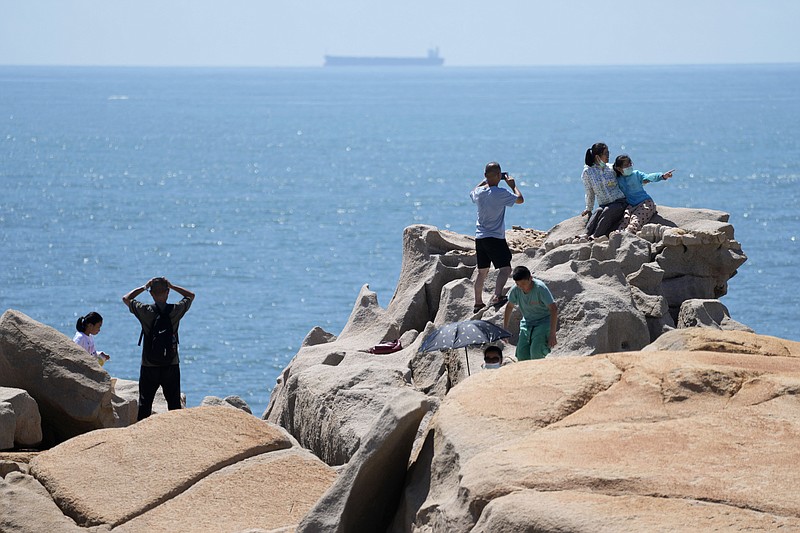 Tourists take photos on the waterfront at the 68-nautical-mile scenic spot, the closest point in mainland China to the island of Taiwan, in Pingtan in southeastern China's Fujian Province Friday. China conducted "precision missile strikes" Thursday in waters off Taiwan's coasts as part of military exercises that have raised tensions in the region to their highest level in decades following a visit by U.S. House Speaker Nancy Pelosi. - Photo by Ng Han Guan of The Associated Press
