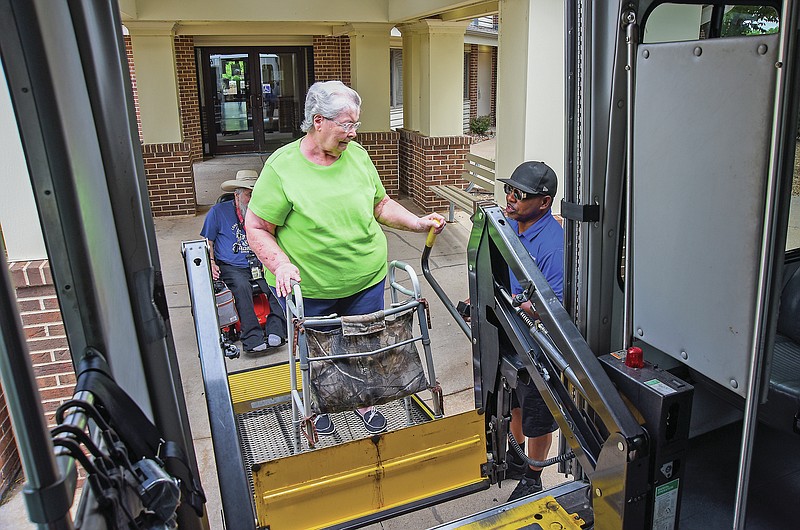 Janet Steele waits under a canopy Thursday, Aug. 4, 2022, at Hyder Apartments as Jefftran driver Michael Henderson lowers the lift for her to safely get into a Handi Wheels bus. Steele said she likes the independence this service offers her. (Julie Smith/News Tribune photo)