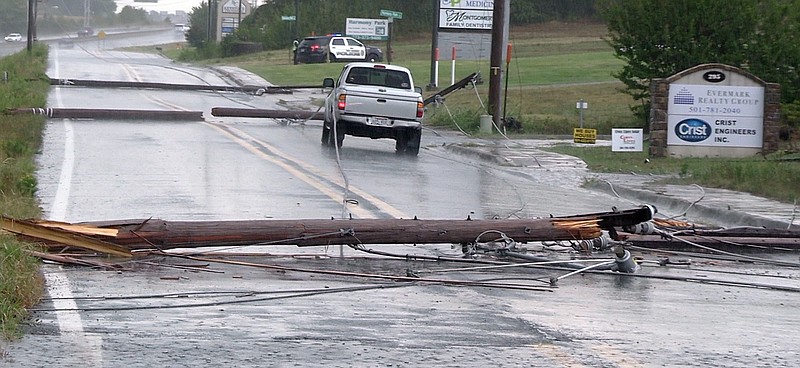 Downed utility poles block a pickup truck in the eastbound lane of Section Line Road on Monday afternoon after a severe thunderstorm moved through the area. Both lanes of the roadway were blocked near Abbott Place. - Photo by Andrew Mobley of The Sentinel-Record