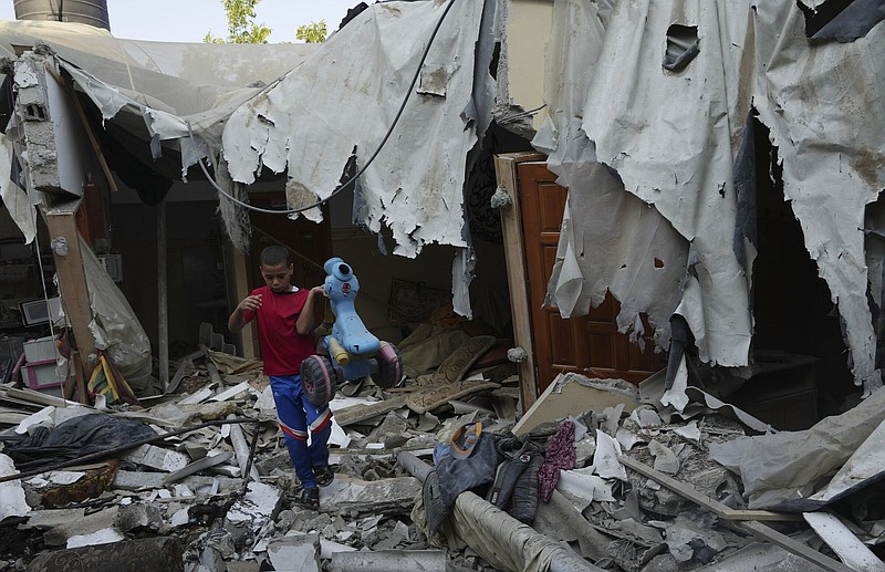 Mohammad Arada removes a tricycle from the rubble of his family house after it was destroyed by an Israeli airstrike, in Rafah refugee camp, southern Gaza Strip, Monday, Aug. 8, 2022. A fragile cease-fire deal to end nearly three days of fighting between Israel and Palestinian militants in Gaza held into Monday morning - a sign the latest round of violence may have abated. (AP Photo/Adel Hana)