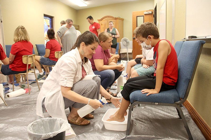 LYNN KUTTER ENTERPRISE-LEADER
Jamie Webb of Farmington washes the feet of Trevor Cruse, 7, during the Farmington Back to School Bonanza last week. Cruse goes to Buttermilk Elementary School in Fayetteville.