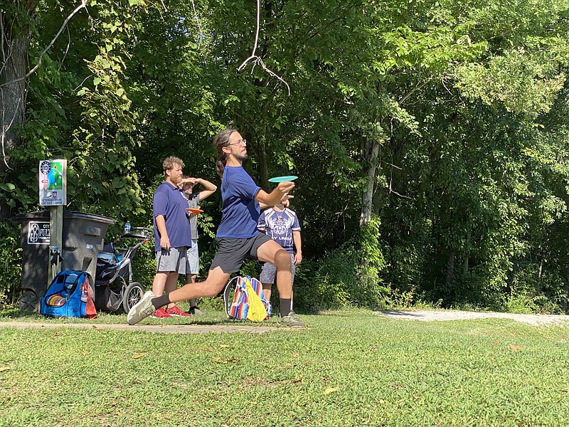 A disc golfer launches a disc towards the basket, which was across the pond at Veteran's Park.