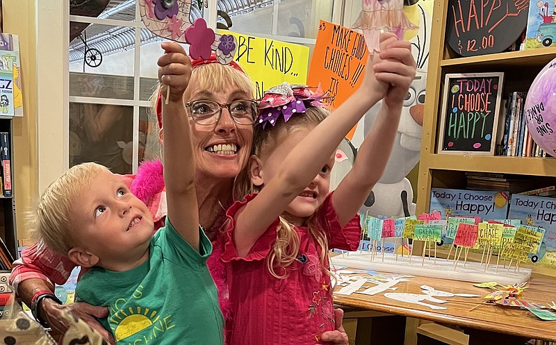 During a recent back-to-school block party in Van Buren, Fort Smith seventh-grade science teacher Patti Farris hugs two youngsters who are showing off crafts made during her book reading. is devoting her semi-retirement to encouraging children to make conscious decisions through a series of books she is self-publishing.
(Special to the Democrat-Gazette/Cheryl Scott)