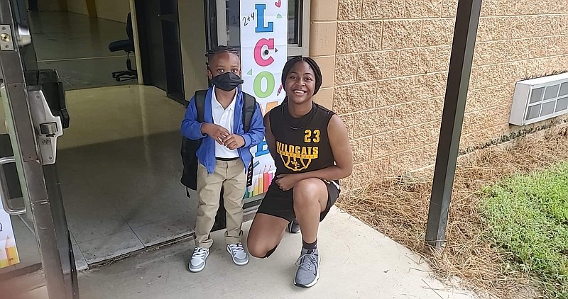 Makayla Earl, small forward for the Watson Chapel High School girls basketball team, guides first-grader Gary Williams from car to classroom at Edgewood Elementary School. (Pine Bluff Commercial/Suzi Parker)
