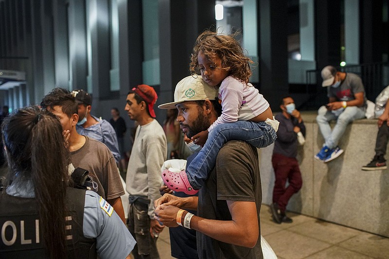 Elier Salazar Chacon, 29, carries 3-year-old daughter Cataleya Salazar Ramirez while speaking with a police officer after arriving on a bus with other migrants from Texas on Wednesday, Aug. 31, 2022, at Union Station in Chicago. (Armando L. Sanchez/Chicago Tribune/TNS)