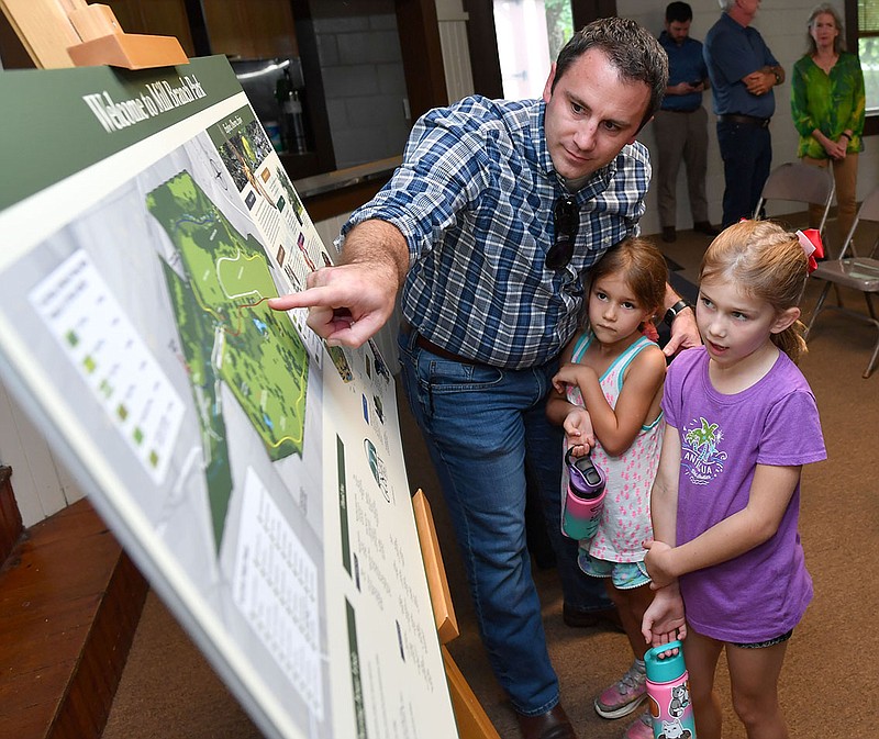 Adam Walker (from left), a member of the Goshen Parks and Recreation Commission, points out details Friday, Sept. 2, 2022, of the newly dedicated Mill Branch Park to daughters Keira Walker, 5, and Arianna Walker, 7, during a ribbon cutting and dedication ceremony for the park at the town’s community center in Goshen. The 104-acre park is the product of two years of work, largely on the part of volunteers and the city’s parks commission and is home to the original 1859 homestead of the first known European settlers in the area as well as many diverse natural features. Visit nwaonline.com/220903Daily/ for today's photo gallery. 
(NWA Democrat-Gazette/Andy Shupe)