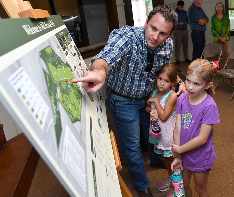 Adam Walker (from left), a member of the Goshen Parks and Recreation Commission, points out details Friday of the newly dedicated Mill Branch Park to daughters Keira Walker, 5, and Arianna Walker, 7, during a ribbon-cutting and dedication ceremony for the park at the town’s community center in Goshen. The 104-acre park is the product of two years of work, largely on the part of volunteers and the city’s parks commission and is home to the original 1859 homestead of the first known European settlers in the area as well as many diverse natural features. Visit nwaonline.com/220903Daily/ for today’s photo gallery.

(NWA Democrat-Gazette/Andy Shupe)