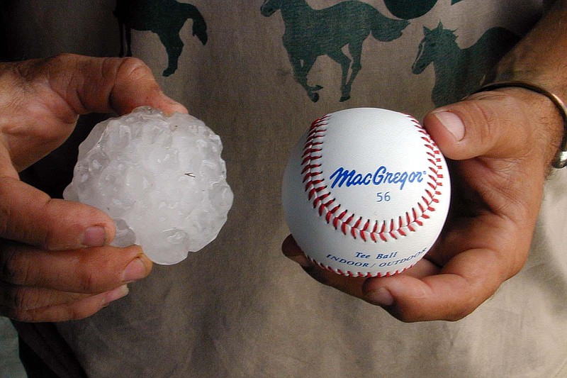 John Cribb holds a hailstone in one hand and a baseball the same size as hail that damaged the windshield of his pickup truck in Horatio on May 28, 2001. (AP Photo/De Queen Daily Citizen, Billy Ray McKelvy)