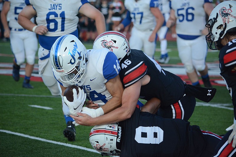 BENNETT HORNE/MCDONALD COUNTY PRESS Mustang defenders Weston Gordon (46) and Joshua Pacheco (8) bring down Marshfield quarterback Joe Harles in the opening quarter of McDonald County's 35-13 win Friday, Sept. 2, at Mustang Stadium.