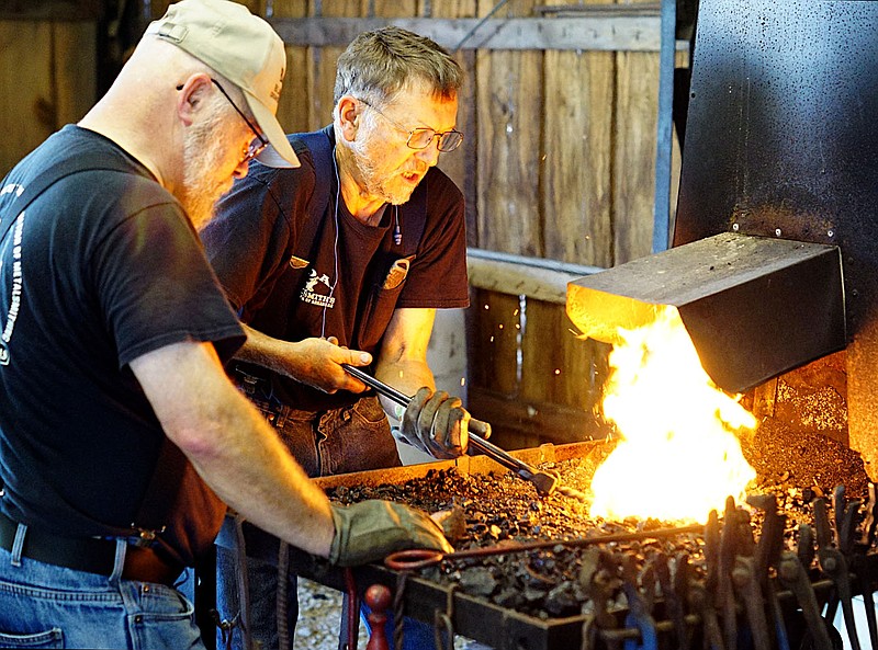 Westside Eagle Observer/RANDY MOLL
While Joe Commerford of Huntsville (left) looks on, Joe Doster, also of Huntsville, heats up the piece of iron Commerford is working on during the Blacksmiths of Arkansas demonstration at the Tired Iron of the Ozarks fall show on Saturday.