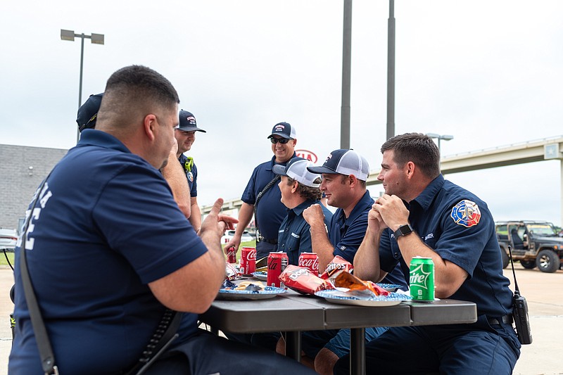 Michael Clark, Nick Smith, Keith Jansen, Jordan Kegley, Greg Auction, Wayne Raschke, Justin Anderson, Clay Phillips and Dakota Johnson from the Texarkana, Texas Fire Department enjoy a complimentary cheeseburger sack lunch with chips and a drink on Saturday at the Texarkana Harley Davidson.  Texarkana Harley Davidson anticipates giving away over 200 cheeseburger lunches throughout the day during the First Responders Appreciation Lunch and 9/11 Memorial Ride.  (Staff photo by Erin DeBlanc)
