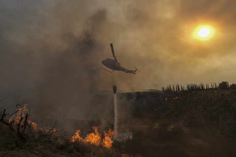 ARCHIVO - Un helicóptero lanza agua sobre el incendio Fairview en una ladera el jueves 8 de septiembre de 2022, cerca de Hemet, California. (AP Foto/Ringo H.W. Chiu, archivo)
