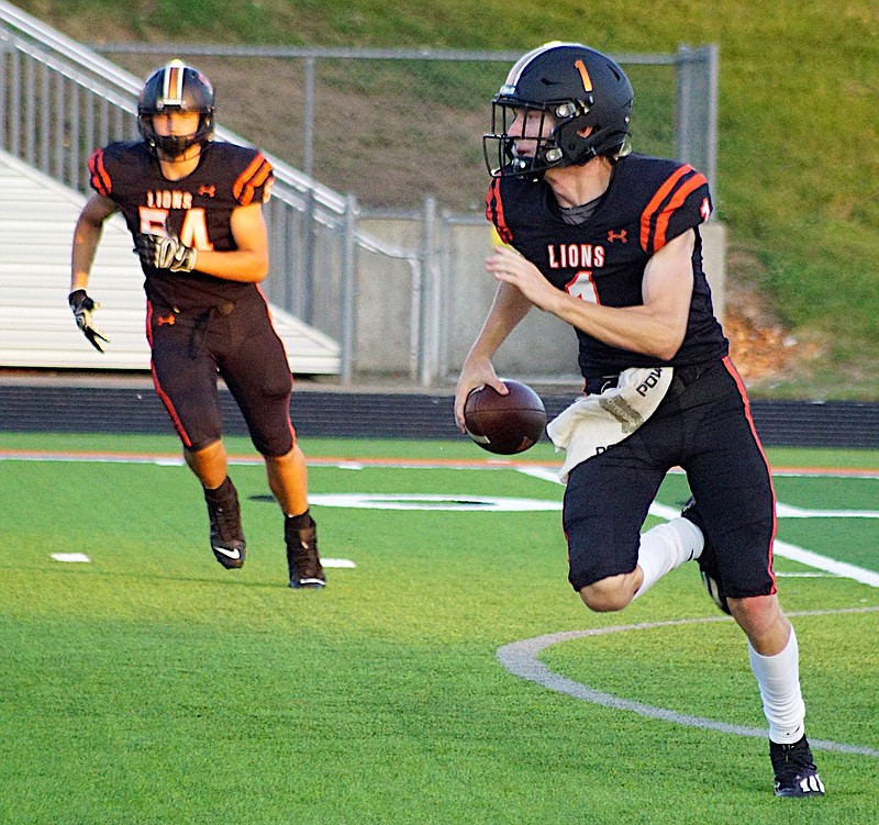 Westside Eagle Observer/RANDY MOLL
With sophomore Aidan Holloway in the background, Gravette's senior quarterback, Rhett Hilger, runs with the ball while looking for an open receiver downfield during Friday night's home game against Prairie Grove.