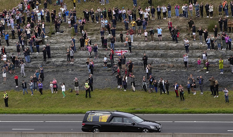 Spectators watch as the cortege with the hearse carrying the coffin of Queen Elizabeth II drives on the M90 motorway as it makes its journey to Edinburgh from Balmoral in Scotland, Sunday, Sept. 11, 2022. The Queen's coffin is being transported Sunday on a journey from Balmoral to the Palace of Holyroodhouse in Edinburgh, where it will lie at rest before being moved to London later in the week. (AP Photo/Alastair Grant)