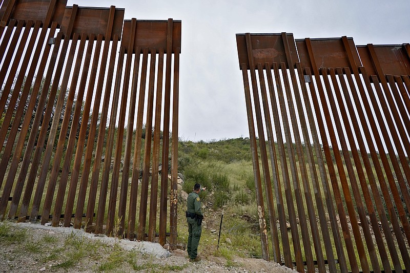U.S. Border Patrol agent Jesus Vasavilbaso looks into Mexico at a breach in the 30-foot-high border wall where a gate was never installed due to a halt in construction on Thursday, Sept. 8, 2022, in Sasabe, Ariz. The wall, in a region at the base of the Baboquivari Mountains located in the Tucson sector, is one of the deadliest stretches along the international border with rugged desert mountains, uneven topography, washes and triple-digit temperatures in the summer months. Border Patrol agents performed 3,000 rescues in the sector in the past 12 months. (AP Photo/Matt York)