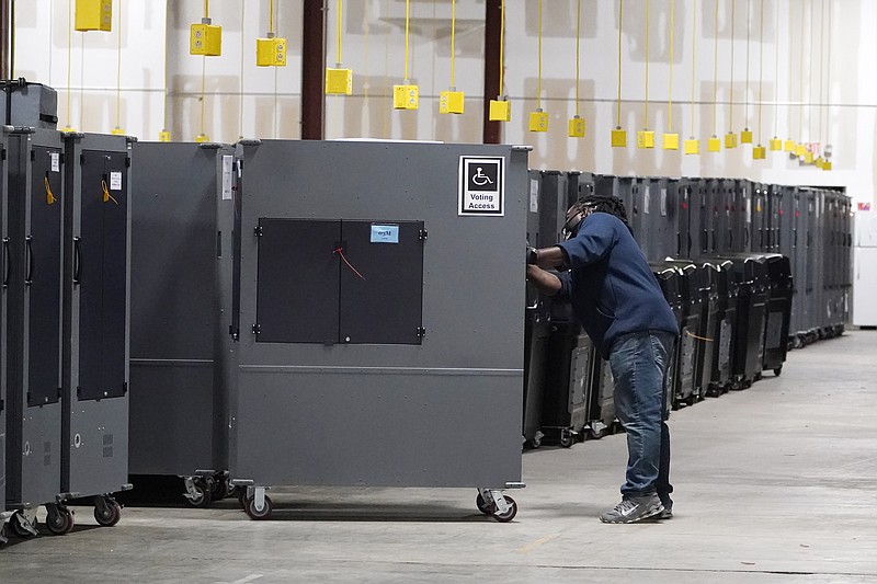 A worker returns voting machines to storage at the Fulton County Election preparation Center on Nov. 4, 2020, in Atlanta. The list of security breaches at local election offices since the 2020 election keeps growing, with investigations ongoing in at least three states, Colorado, Georgia and Michigan. Security experts say the breaches by themselves have not necessarily increased threats to the November elections, but say they increase the possibility that rogue election workers could access election equipment to launch attacks. (AP Photo/John Bazemore, File)