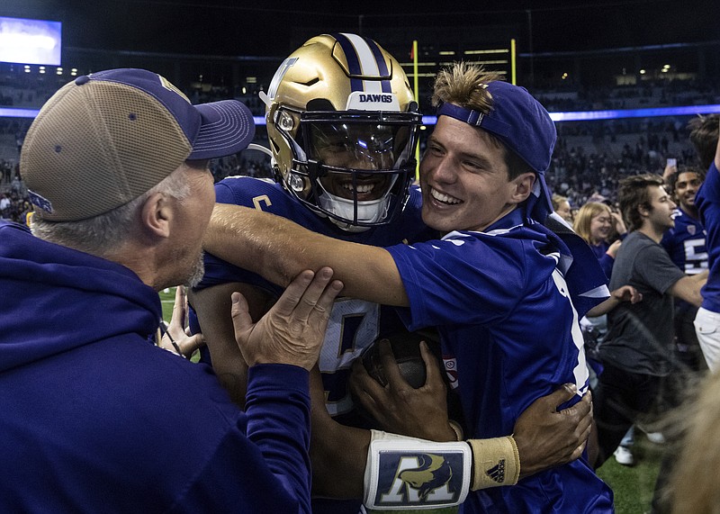 Fans celebrate with Washington quarterback Michael Penix Jr., center, after an NCAA college football game against Michigan State, Saturday, Sept. 17, 2022, in Seattle.  (AP Photo/Stephen Brashear)