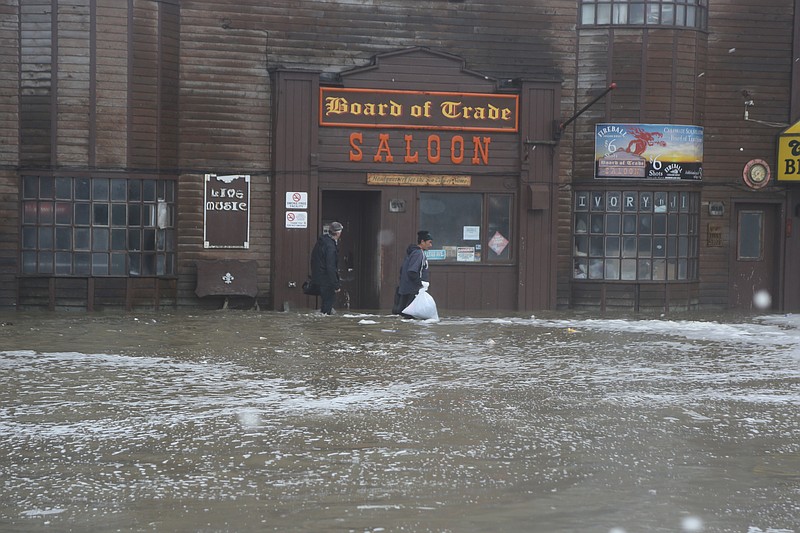 Two men walk through rushing water on Front Street, just a half block from the Bering Sea, in Nome, Alaska, on Saturday, Sept. 17, 2022. Much of Alaska's western coast could see flooding and high winds as the remnants of Typhoon Merbok moved into the Bering Sea region. The National Weather Service says some locations could experience the worst coastal flooding in 50 years. (AP Photo/Peggy Fagerstrom)