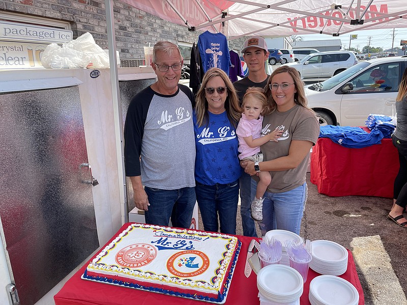 Democrat photo/Kaden Quinn:  
From left, owner Norris Gerhart prepares to cut Mr. G's Liquor 43rd anniversary cake with his wife Lesley, son-in-law Quinn Hindman, daughter Missy Hindman and granddaughter Rowan Hindman.