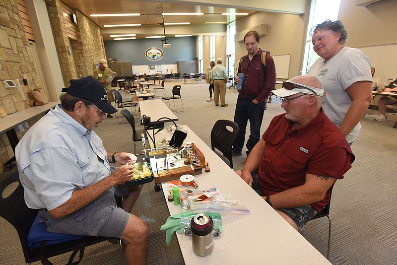 (NWA Democrat-Gazette/Flip Putthoff)
Gary Rowland with the Bella Vista Fly Tyers club ties fishing flies on Aug. 13 while Tracy and Angelia Franklin of Prairie Grove watch during a fly tying demonstration at the J.B. and Johnelle Hunt Family Ozark Highlands Nature Center in Springdale. Anglers from the Bella Vista Fly Tyers and Trout Unlimited tied an array of flies for catching trout, smallmouth bass and other species.