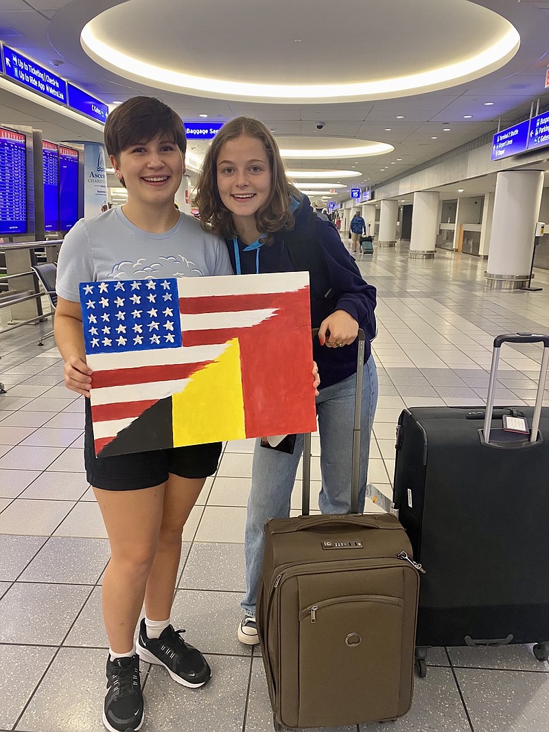 Katherine Stevens, Rotary Youth Exchange Student, prepares to leave for Spain. (Left) Romane Dessy from Belgium, Rotary Youth Exchange student holds a flag.