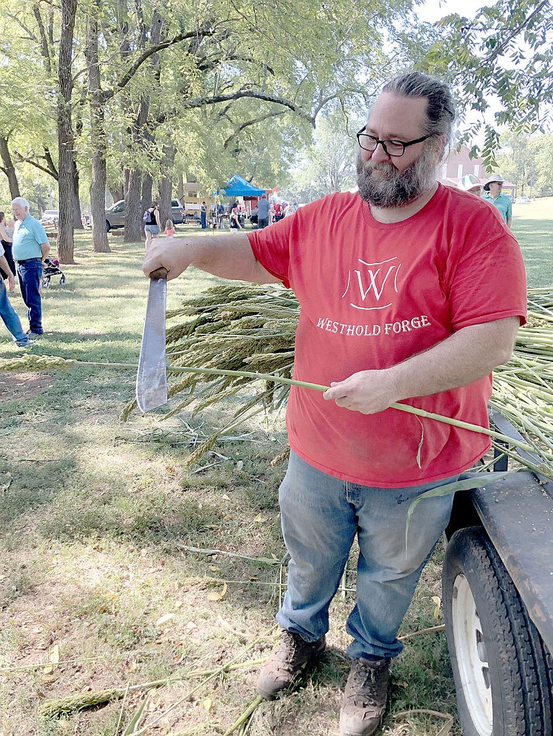 Jeremiah West, a Lincoln resident, shows one of the blades used to cut and trim cane stalks Saturday during the 2022 Cane Hill Harvest Festival. The hard outer casings of cane have to be peeled away from the fibrous, juicy interior which can be chewed, but not swallowed, to extract a sweet liquid.

(Special to NWA Democrat-Gazette/Denise Nemec)