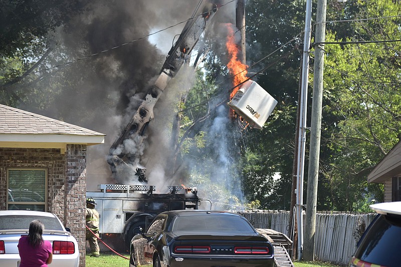 A woman watches as a bucket truck catches on fire near power lines behind a duplex in the 200 block of South Poplar Street in Pine Bluff on Wednesday. (Pine Bluff Commercial/I.C. Murrell)