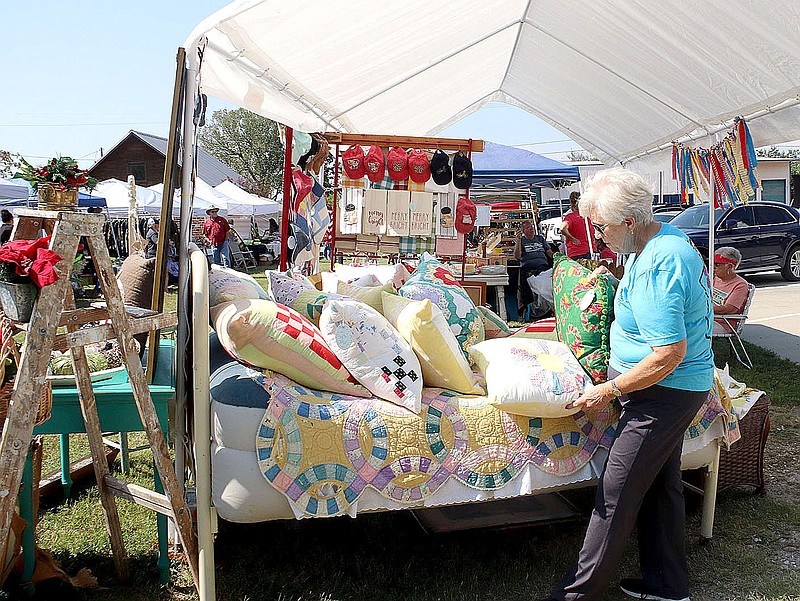 FILE PHOTO Donna Graham of Farmington looks over quilts and quilted pillows at this booth at the 2019 Junk at the Mill, held at the Washington County Milling Co., in Prairie Grove. This year's event will be Friday and Saturday.