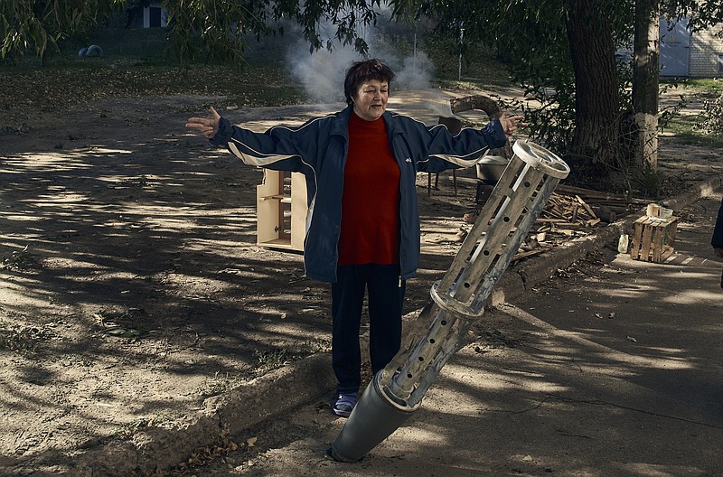 A local resident stands near a rocket fragment near her house in the recently retaken Kupiansk in the Kharkiv region, Ukraine, Wednesday, Sept. 21, 2022. (AP Photo/Kostiantyn Liberov)