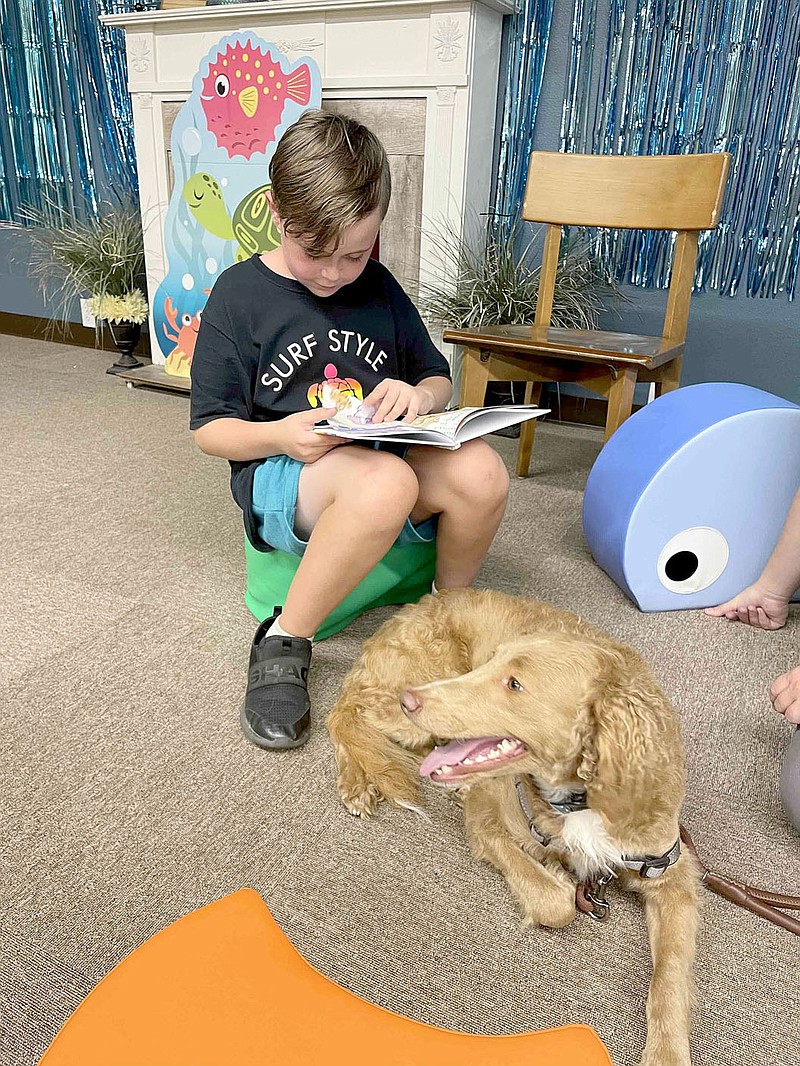 COURTESY PHOTO
Liam Thulin, 10, reads to Liya, a golden doodle owned by Michelle Tabor, at Prairie Grove Public Library during a program called Reading With Dogs organized by Erica Jones with Cajun Lady K9 in Prairie Grove. Parents had to call and reserve a spot for their children to be able to read to a dog.