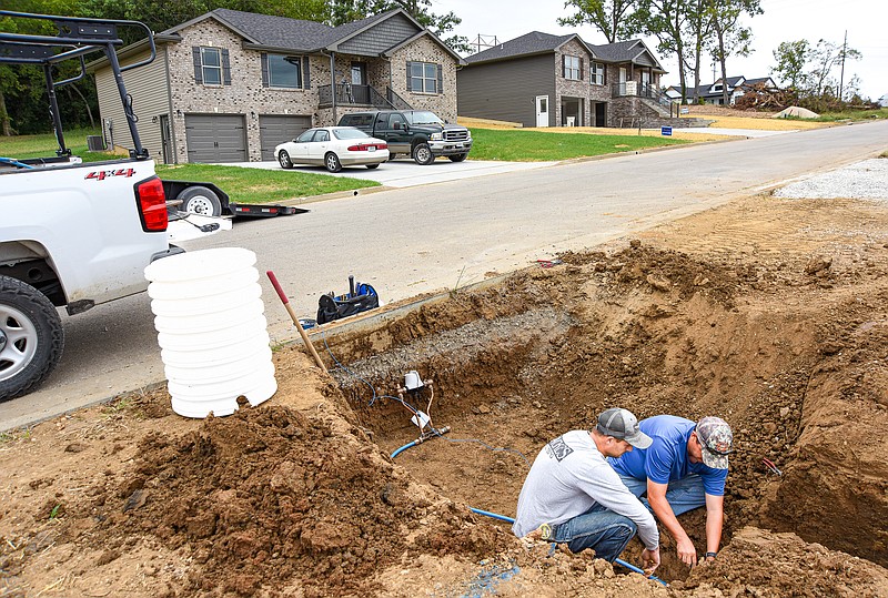 Julie Smith/News Tribune
Scot Nilges, right, and  Derick Backes, install a water line into a new home under construction in SummerField Estates. Nilges is a service technician with Public Water District No. 1 while Backes is with Backes Plumbing. Backes Plumbing has work scheduled for multiple new builds in the near distant future. Backes and other contractors were at work in the new subdivision off of Old Lohman Road, where multiple houses are in various stages of construction. Realtors do expect the housing market to cool slightly over the next few months.