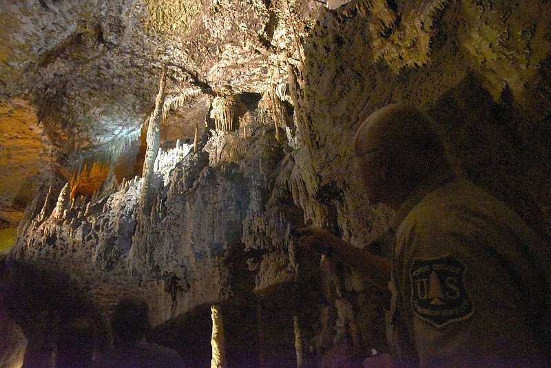 Flip Putthoff/NWA Democrat-Gazette Cave formations, such as these seen on Aug. 25 near the ceiling of a massive Blanchard Springs Cavern room, take centuries to form. A guide (right) explains how the features are formed.