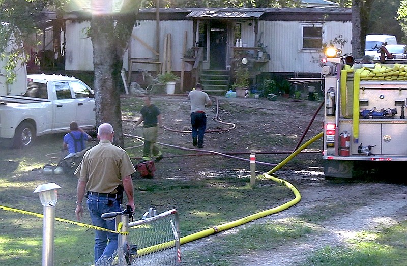 Garland County Coroner Stuart Smedley, left, walks to the scene of a fatal house fire at 264 Old Church Road Thursday evening. - Photo by Andrew Mobley of The Sentinel-Record