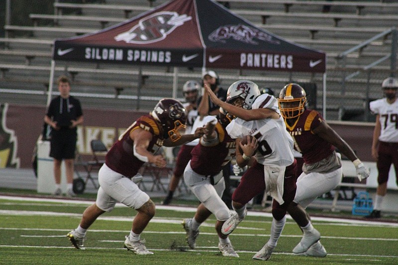 Siloam Springs' Jackson Still (6) tries to escape from Lake Hamilton's Kendrick Martin (1), Justin Crutchmer (5) and Izic Clenney (20) Friday at Wolf Stadium. - Photo by Lance Porter of The Sentinel-Record