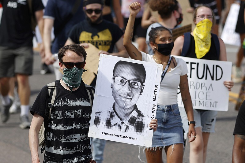 A demonstrator carries an image of Elijah McClain during a rally and march June 27, 2020, in Aurora, Colo. A Colorado judge on Friday, Sept. 16, 2022, responded to a request by a coalition of news organizations to release an amended autopsy report for Elijah McClain, a 23-year-old Black man who died after a 2019 encounter with police, by ruling the report be made public only after new information it contains is redacted. (AP Photo/David Zalubowski, File)