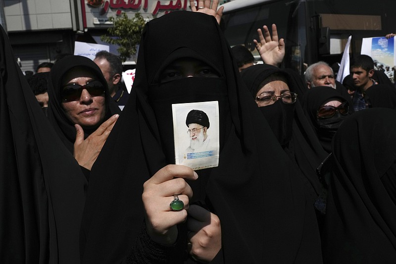 A pro-government demonstrator holds a picture of the Iranian Supreme Leader Ayatollah Ali Khamenei while attending a rally after prayers to condemn recent anti-government protests over the death of a young woman in police custody Friday, Sept. 23, 2022, in Tehran, Iran. The crisis unfolding in Iran began as a public outpouring over the the death of Mahsa Amini, a young woman from a northwestern Kurdish town who was arrested by the country's morality police in Tehran last week for allegedly violating its strictly-enforced dress code. (AP Photo/Vahid Salemi)