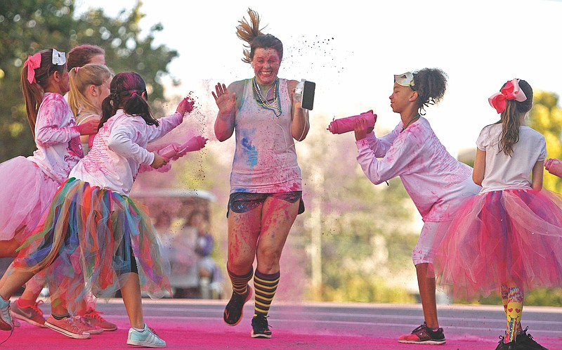 Cristina Lee is showered in a cloud of pink as she participates the Paint the Town Pink 5k run/walk on Saturday, October 6, 2018. (News-Times file)
