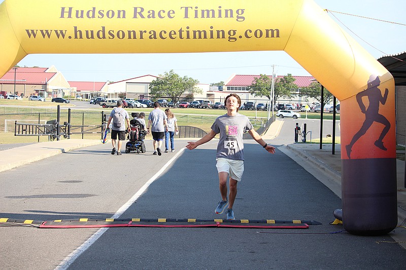 Christopher Bennett crosses the finish line at the inaugural Princess Nora’s Warrior 5K fundraiser outside Wolf Arena Saturday morning. - Photo by Krishnan Collins of The Sentinel-Record