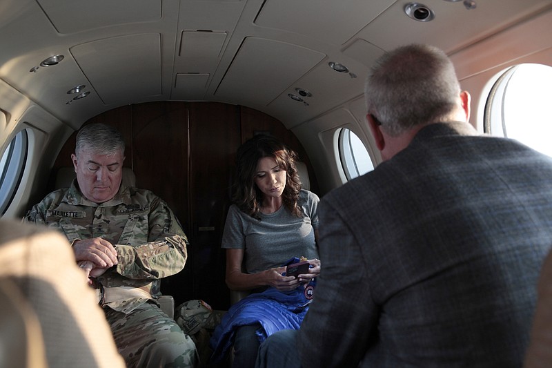 FILE - South Dakota Gov. Kristi Noem, center, checks her phone before taking off, Monday, July 26, 2021 in Pierre, S.D.  Noem is under investigation for using a state-owned airplane to fly to political events and bring family members with her on trips. But the decision on whether to prosecute the Republican governor likely hinges on how a county prosecutor interprets an untested law that was passed by voters in 2006. (AP Photo/Stephen Groves)