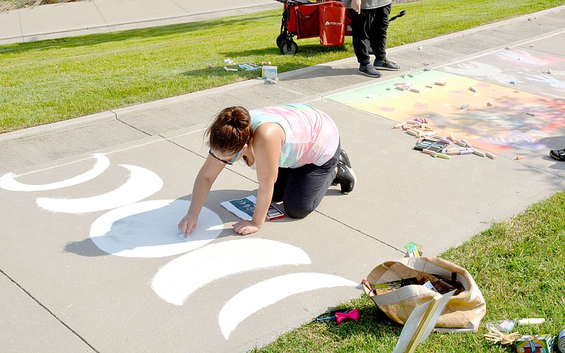 Marc Hayot/Herald-Leader Cristal Avalos, part of the Hive draws the phases of the moon as her children and fellow Hive members have gone to check out other areas of Chalk It Up on Saturday at Memorial Park. Avalos' work paid off as the Hive took first place in the 18+ category.
