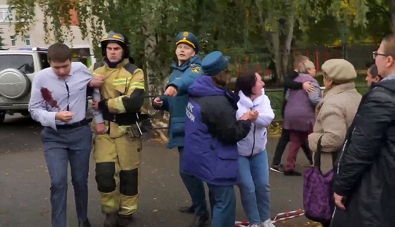 In this image taken from video, emergency situation employees help wounded people to escape the scene of a shooting at school No. 88 on Monday, Sept. 26, 2022, in Izhevsk, Russia. Authorities say a gunman has killed 15 people and wounded 24 others in the school in central Russia. According to officials, 11 children were among those killed in the Monday morning shooting. (Izhlife.ru via AP)