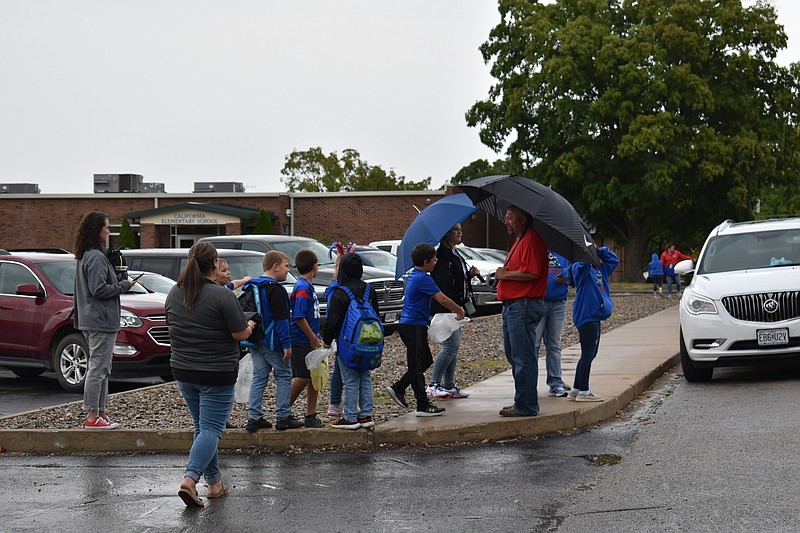 Democrat photo/Garrett Fuller — With their umbrellas to keep them dry, people prepare for the California Homecoming parade to start Friday (Sept. 23, 2022,) on South Owen Street in front of California Middle School.