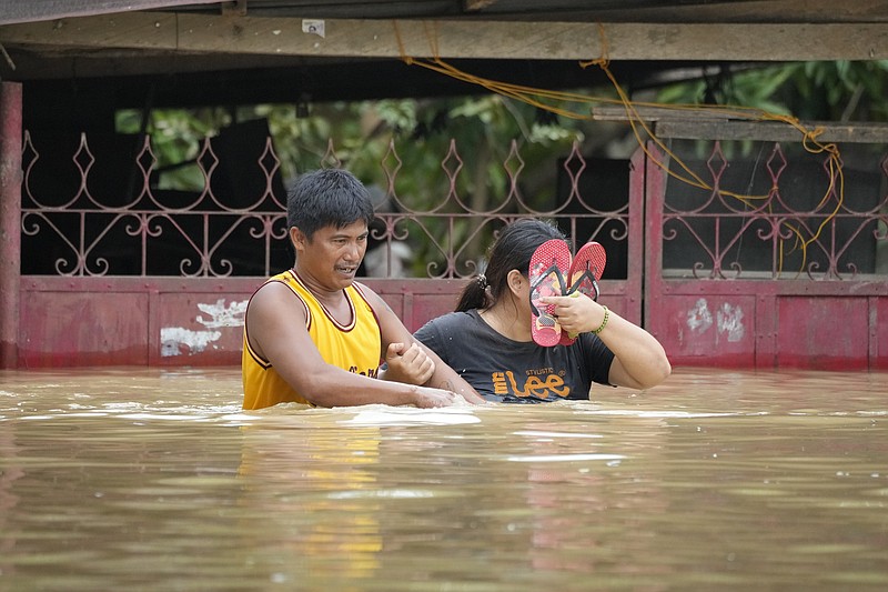 Residents negotiate a flooded road due to Typhoon Noru in San Miguel town, Bulacan province, Philippines, Monday, Sept. 26, 2022. Typhoon Noru blew out of the northern Philippines on Monday, leaving some people dead, causing floods and power outages and forcing officials to suspend classes and government work in the capital and outlying provinces. (AP Photo/Aaron Favila)