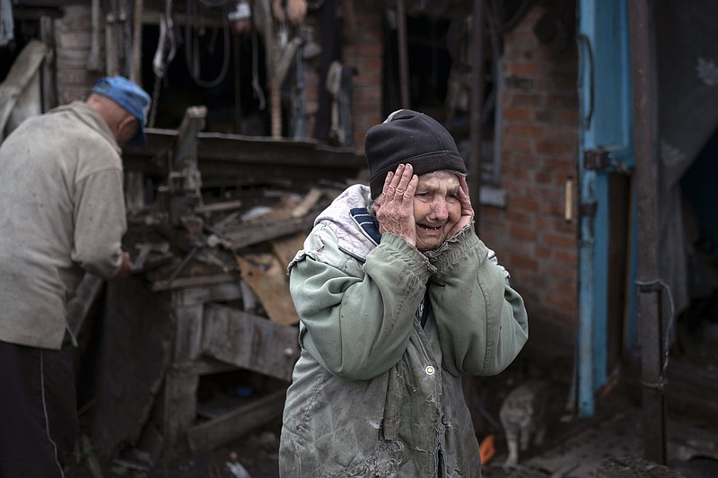 Valentina Bondarenko reacts as she stands with her husband Leonid outside their house that was heavily damaged after a Russian attack in Sloviansk, Ukraine, Tuesday, Sept. 27, 2022. The 78-year-old woman was in the garden and fell on the ground at the moment of the explosion. "Everything flew and I started to run away", says Valentina. (AP Photo/Leo Correa)